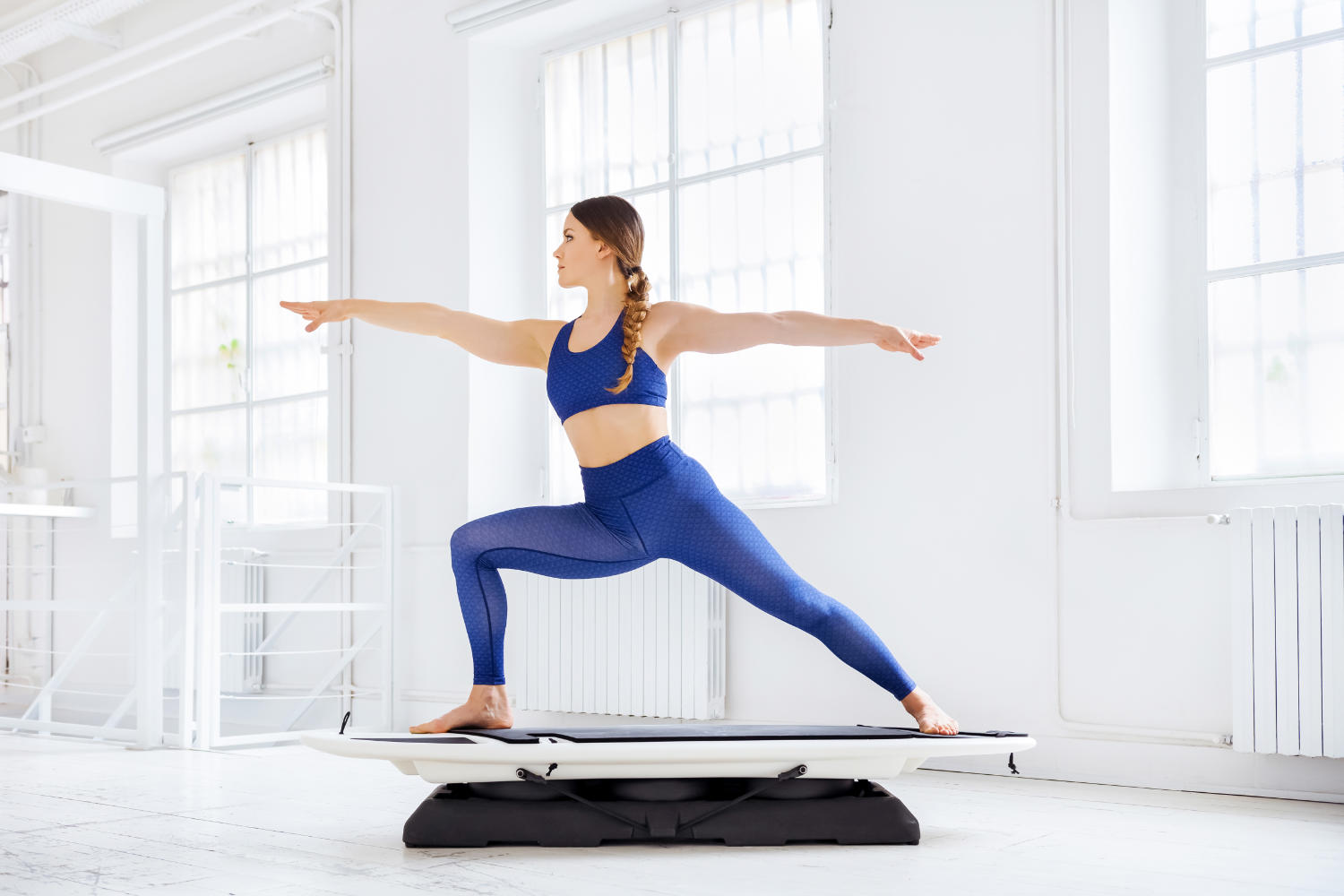 Frau auf einem blance board in Krieger Yoga Position